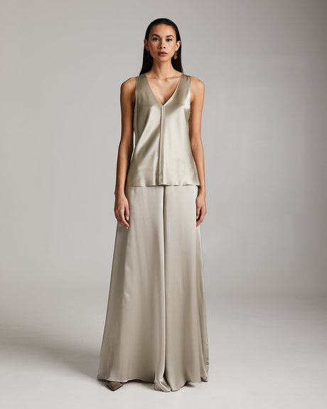 Woman wearing a beige sleeveless top and wide-leg pants against a plain background