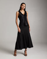 Woman wearing a black sleeveless top and skirt against a gray background