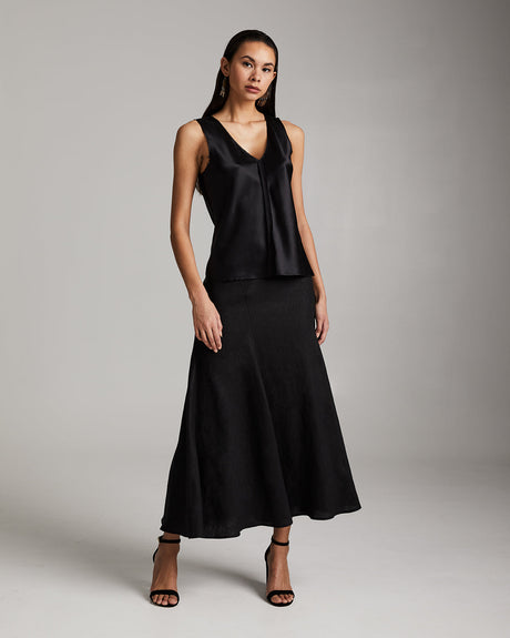 Woman wearing a black sleeveless top and skirt against a gray background