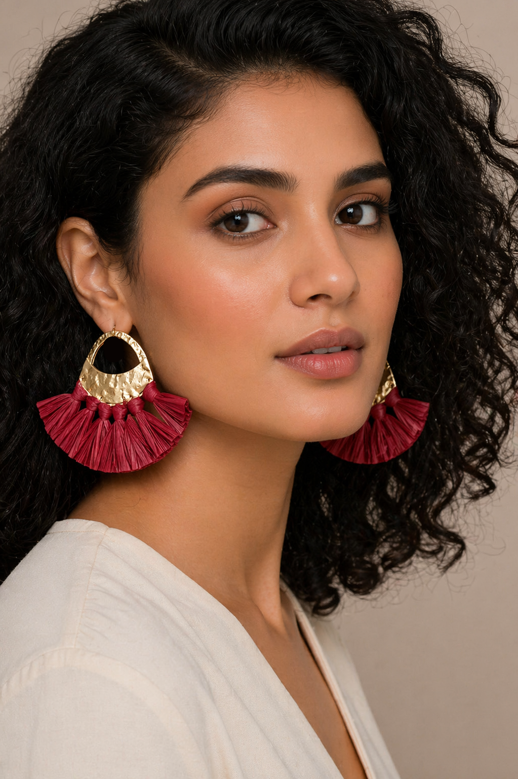 Woman wearing red ruffled earrings with a neutral background