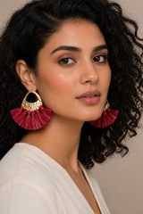 Woman wearing red ruffled earrings with a neutral background