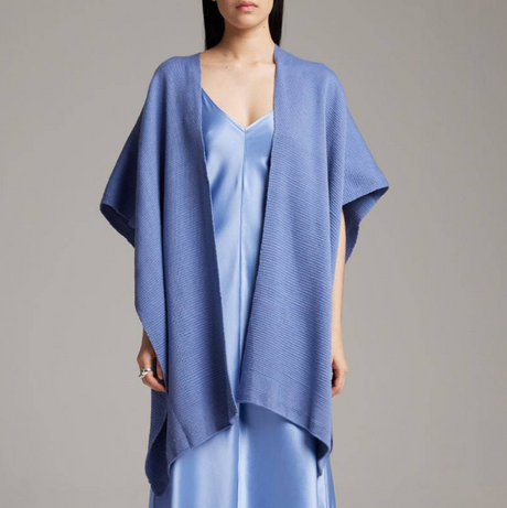 Woman wearing a blue dress with a matching shawl against a gray background