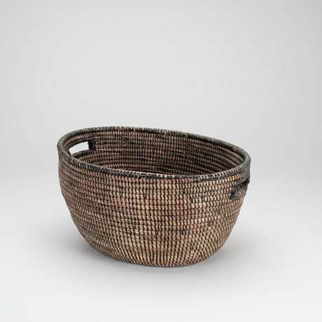 Woven basket with two handles on a light gray background