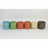 Set of six woven baskets in different colors on a white background