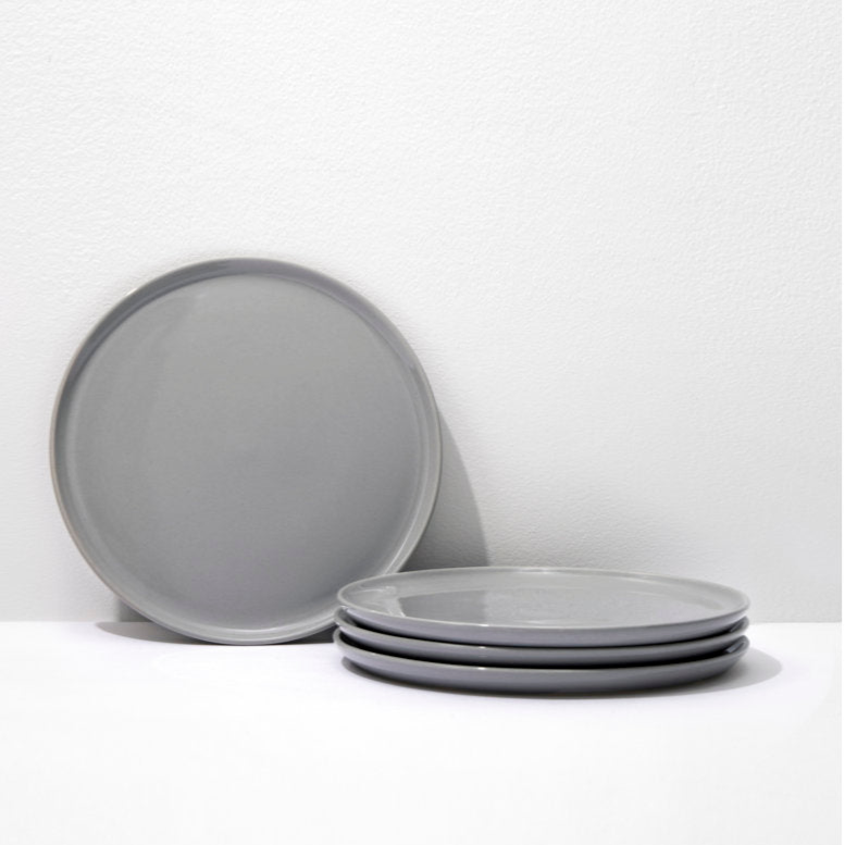 Set of gray ceramic plates on a white surface with a light gray background