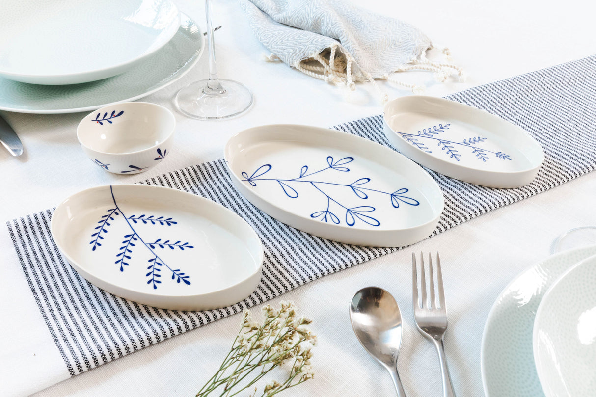 Dinnerware set with blue floral patterns on a striped tablecloth. Süheyla Nesting Plates