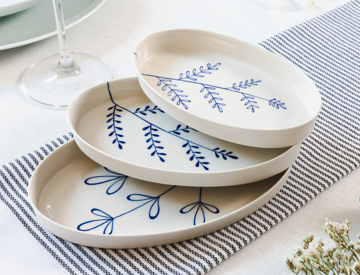 Set of white ceramic plates with blue floral patterns on a striped tablecloth. Süheyla Nesting Plates