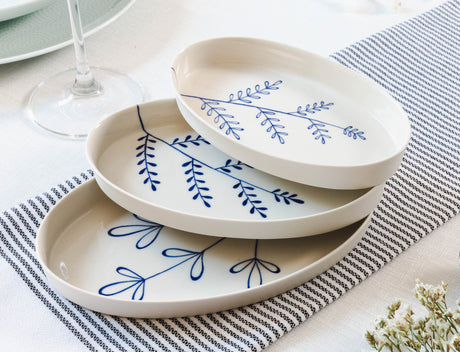 Set of white ceramic plates with blue floral patterns on a striped tablecloth. Süheyla Nesting Plates