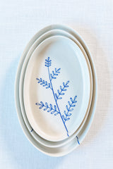 Set of white ceramic plates with blue leaf design on a light blue background. Süheyla Nesting Plates