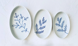 Three oval ceramic plates with blue leaf patterns on a white background. Süheyla Nesting Plates