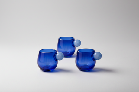 Four blue glass tumblers with unique designs on a wooden surface