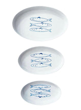 Three white plates with blue fish illustrations on a white background