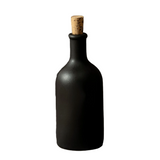 Black bottle with cork next to a lemon on a white background