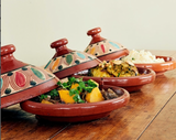 Set of ceramic tagines with food on a wooden table