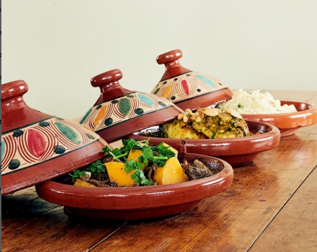 Set of ceramic tagines with food on a wooden table