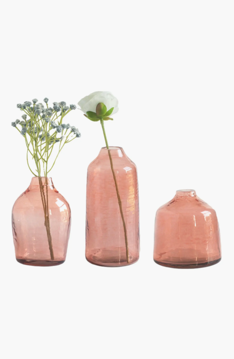Set of three pink glass vases with flowers on a white background