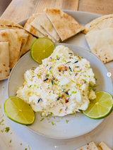 Dip with pita bread and lime wedges on a wooden surface