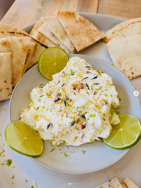 Dip with pita bread and lime wedges on a wooden surface