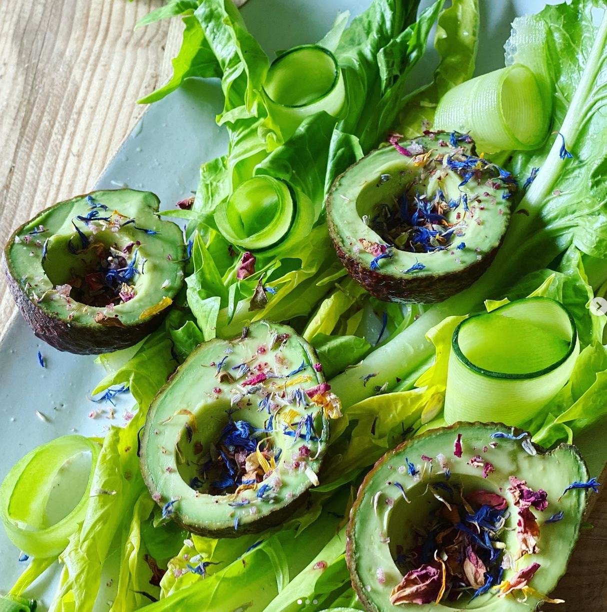 Avocado slices on a bed of lettuce with edible flowers