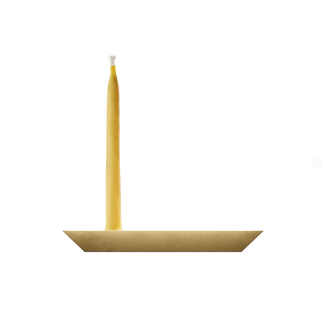 Yellow candle on a gold dish against a white background