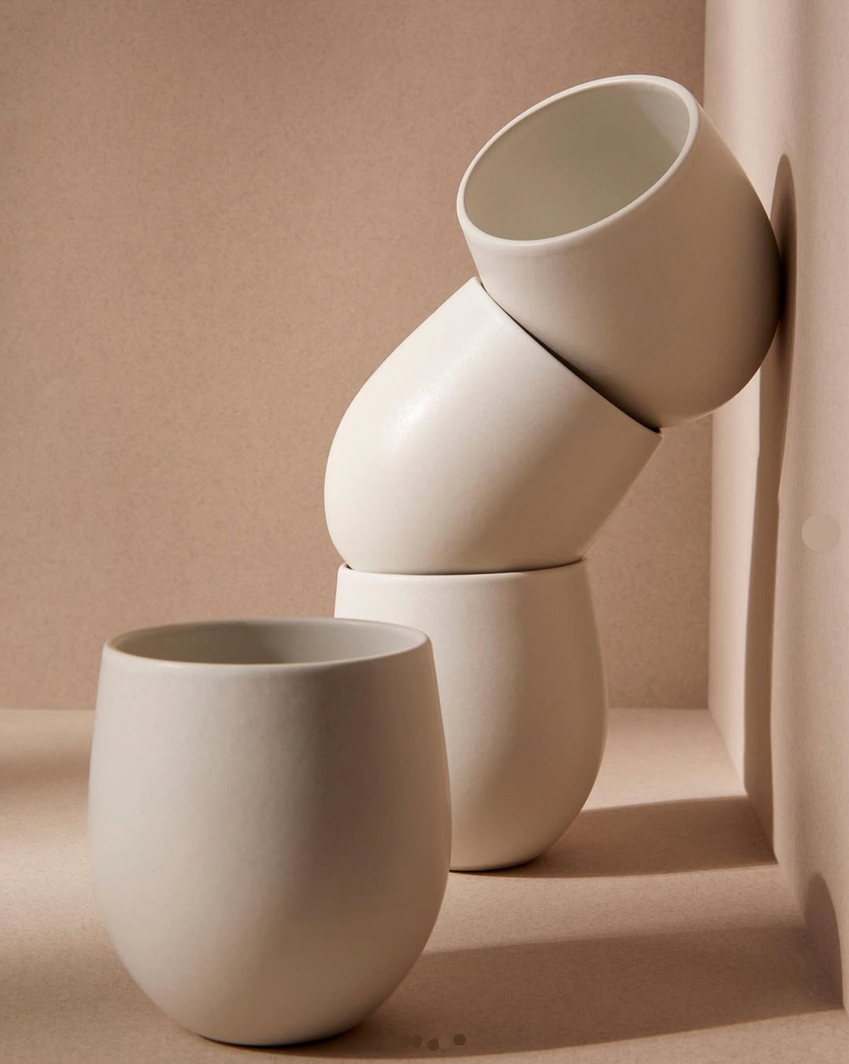 Stack of white ceramic cups on a beige background