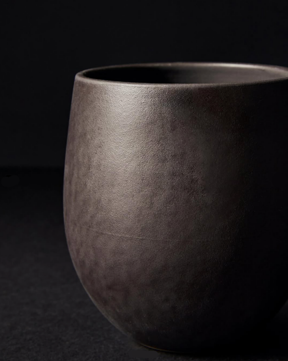 Dark gray ceramic cup on a black background