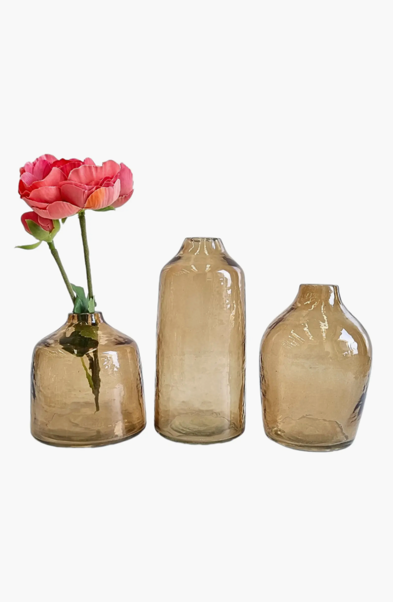 Three brown glass vases of different sizes with a pink flower on a white background