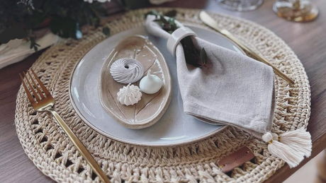 Elegant table setting with crocheted placemat, ceramic plates, and cutlery.