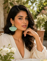 Woman with green earrings sitting at a table with a salad outdoors