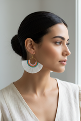 Woman wearing colorful earrings against a neutral background