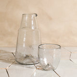 Two clear glass pieces on a tiled surface with a beige wall background
