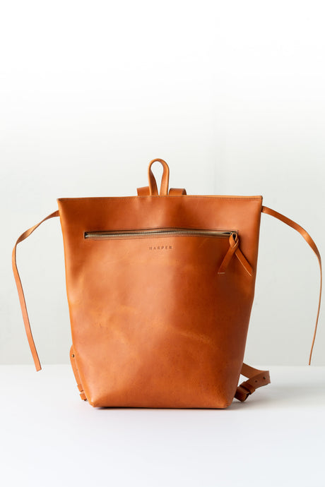The Folded Backpack - Saddle. Brown leather backpack on a white background
