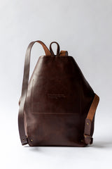 The Folded Backpack - Walnut. Brown leather backpack on a light gray background