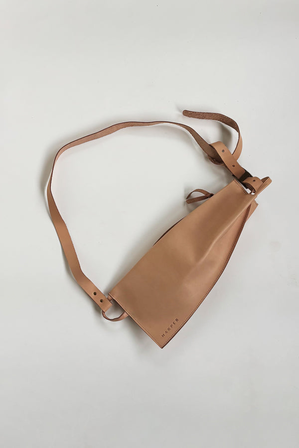 The Offset Sling Bag - Natural. Tan leather crossbody bag on a light gray background