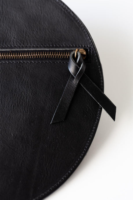 The Pleated Clutch - Black. Black leather pouch with a black ribbon on a white background