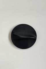 The Pleated Clutch - Black. Black leather clutch on a light gray background