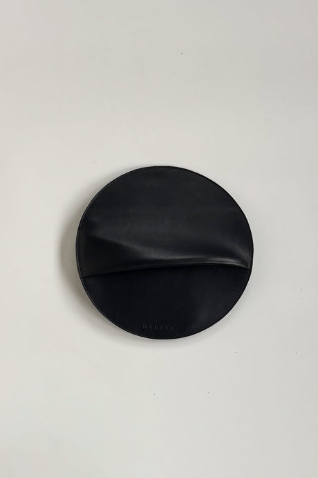 The Pleated Clutch - Black. Black leather clutch on a light gray background