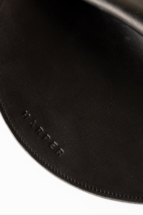 The Pleated Clutch - Black. Close-up of a black leather product with 'HARPER' branding.
