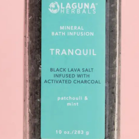 Laguna Herbals Tranquil mineral bath infusion packaging with black lava salt and activated charcoal on a pink background.