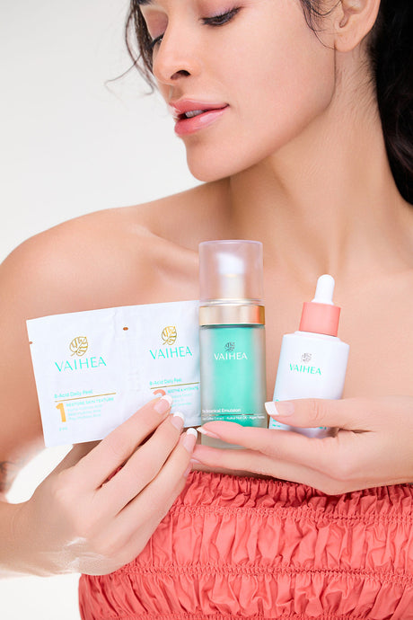 Woman holding Vaihea skincare products against a white background