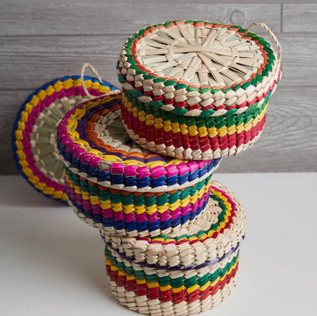 Stack of colorful woven baskets on a light surface with a wooden background