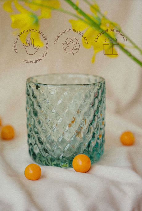 Glass  with textured design on a light background with yellow berries and flowers.