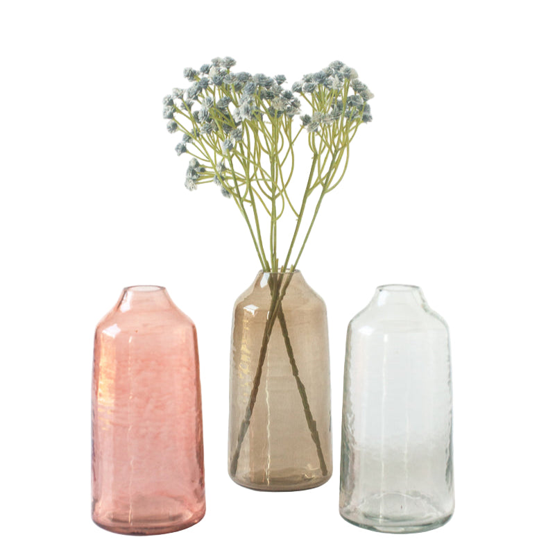 Three glass vases of different colors with a single stem of flowers on a white background
