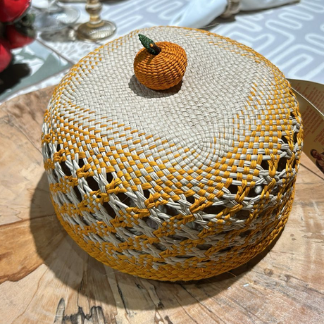 Woven bread basket with a small pumpkin decoration on a wooden surface
