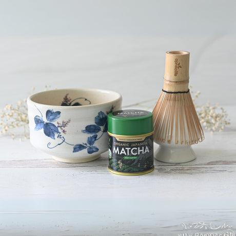 The White Clay Kudzu Flowers Matcha Set features a beautifully crafted Minoyaki pottery bowl, bamboo whisk with holder, and organic Japanese matcha tin. Perfectly arranged on light wood with delicate white flowers in the background, it makes an ideal matcha starter set.