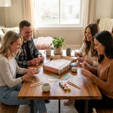 Four people enjoying a pottery-making activity together in a cozy living room.