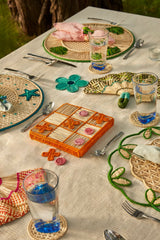 Outdoor table setting with a game board, glasses, and decorative items on a textured surface.