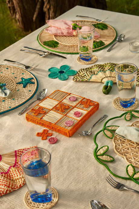 Outdoor table setting with a game board, glasses, and decorative items on a textured surface.