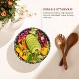 Colorful salad in a durable stoneware bowl with wooden utensils on a light background