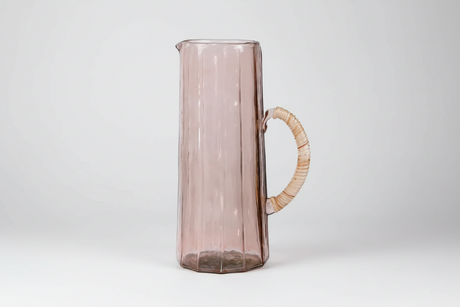 Pink glass pitcher with wooden handle on a white background